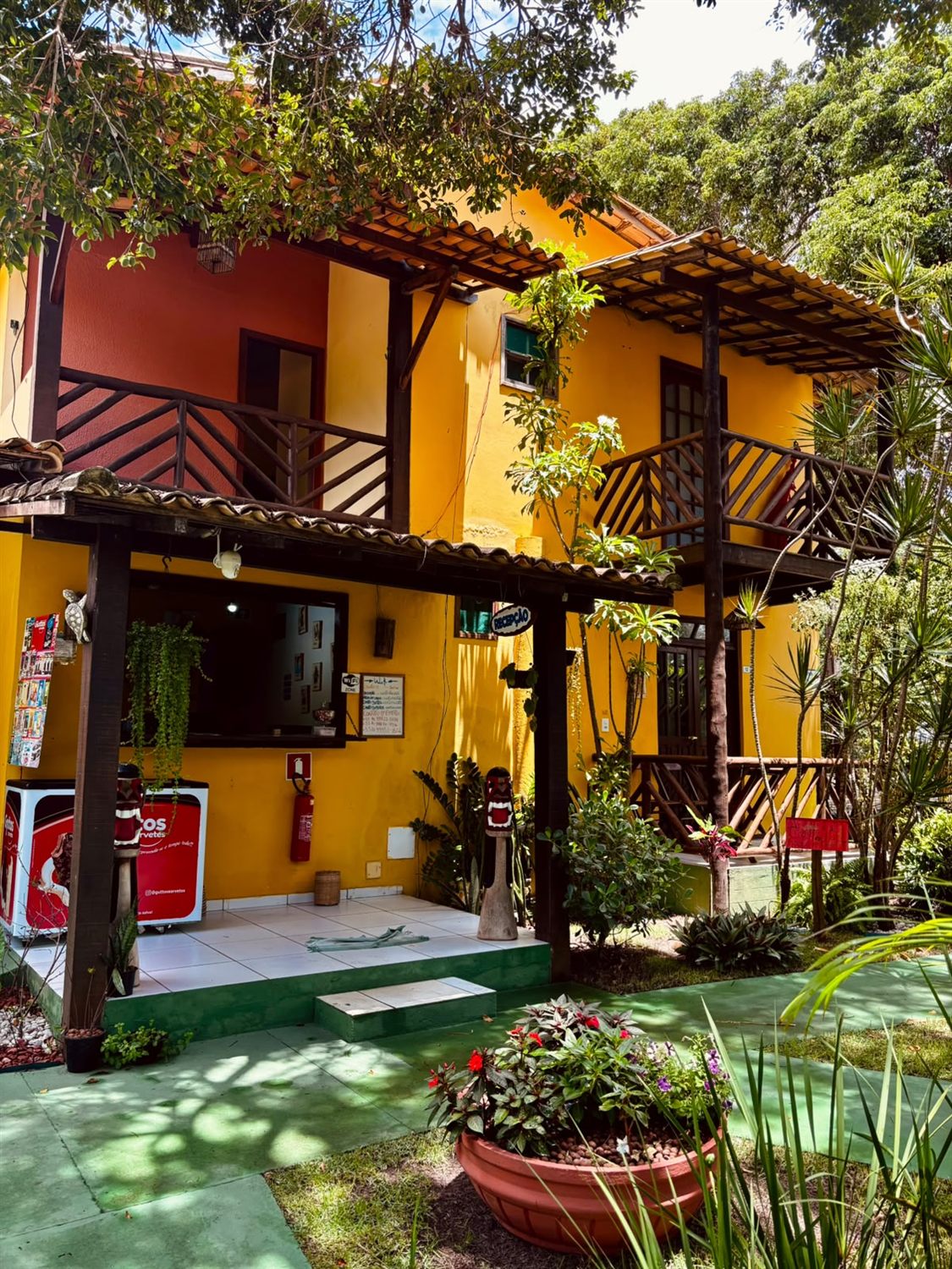 A fachada amarela da pousada e o jardim